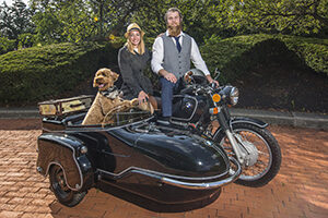 Couple on a BMW motorcycle with dog in sidecar