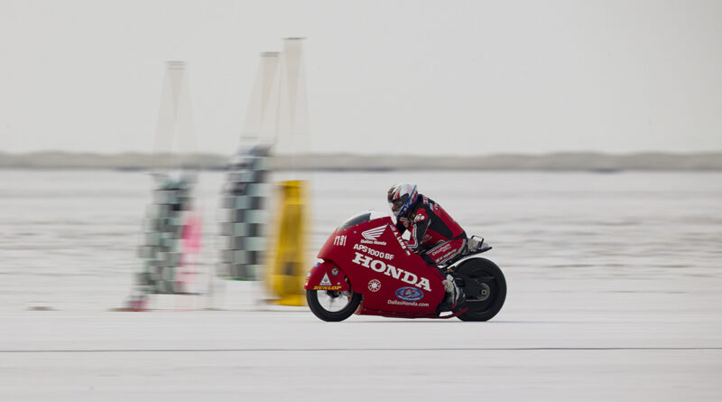 A red honda motorcycle flying by at the AMA Land Speed Grand Championship at the Bonneville Salt Flats